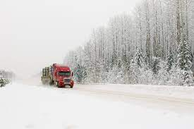 a truck drives on a snowy road in winter