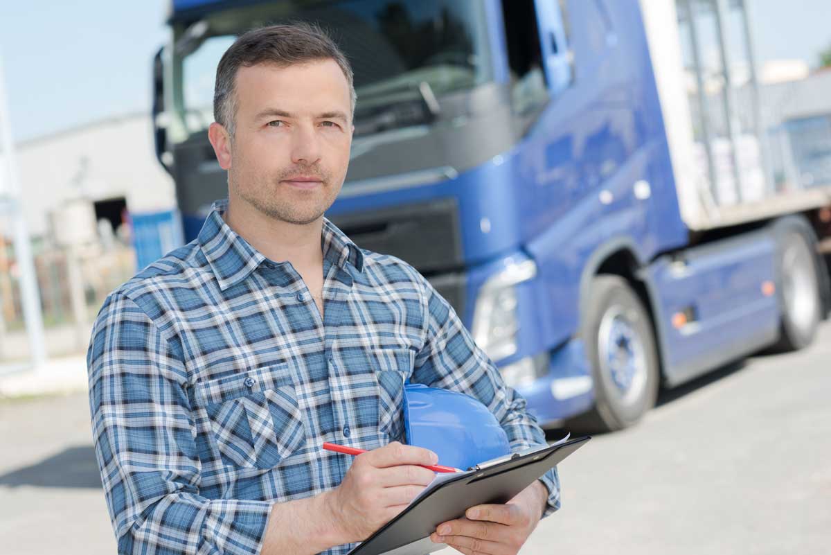 a man holds a clipboard while standing in front of a fleet truck.