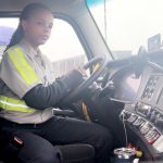 a Source One Truck Driver in the cab of her truck.