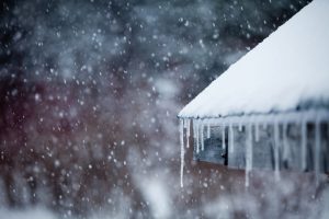 Icicles hang from a room as snow gently falls in the background during Winter.