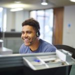 a Smiling Call Center Worker wears a headset while taking calls