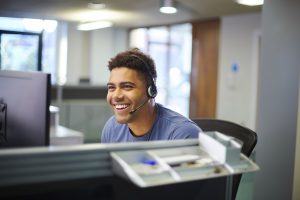 a Smiling Call Center Worker wears a headset while taking calls